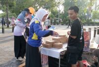 Petugas Sosialisasi Informasi, Kebijakan dan Akses Publik Pontianak (SIKAP) menyerahkan brosur program Pemkot Pontianak kepada masyarakat ketika CFD