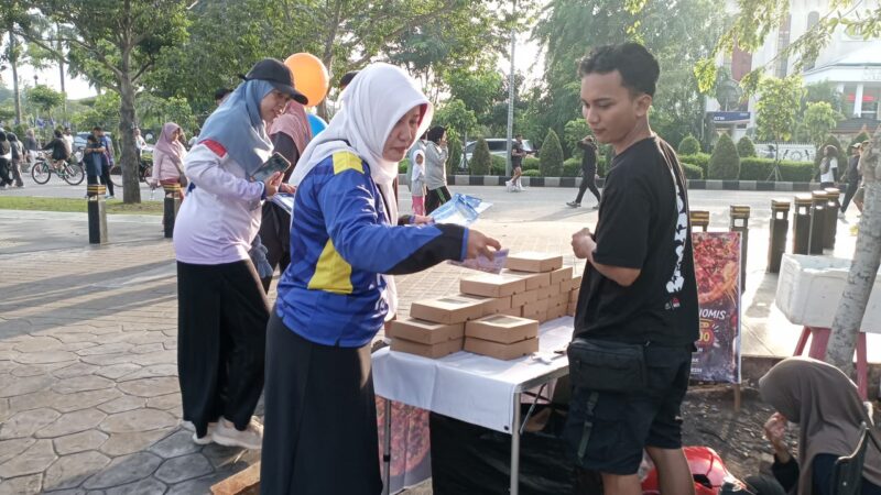 Petugas Sosialisasi Informasi, Kebijakan dan Akses Publik Pontianak (SIKAP) menyerahkan brosur program Pemkot Pontianak kepada masyarakat ketika CFD